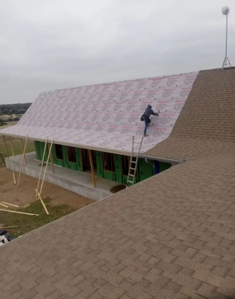 Worker preparing underlayment for a metal roof installation in Eldridge